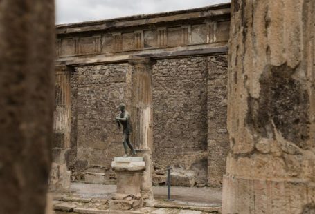 Pompeii Ruins - a statue of a man is in between two pillars