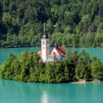 Lake Bled - white and brown concrete building near green trees and lake during daytime