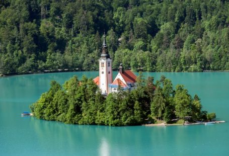 Lake Bled - white and brown concrete building near green trees and lake during daytime
