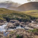 Fairy Pools - river between green grass field under white clouds during daytime
