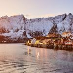 Lofoten - brown wooden house on body of water near mountain during daytime