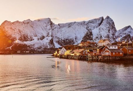 Lofoten - brown wooden house on body of water near mountain during daytime