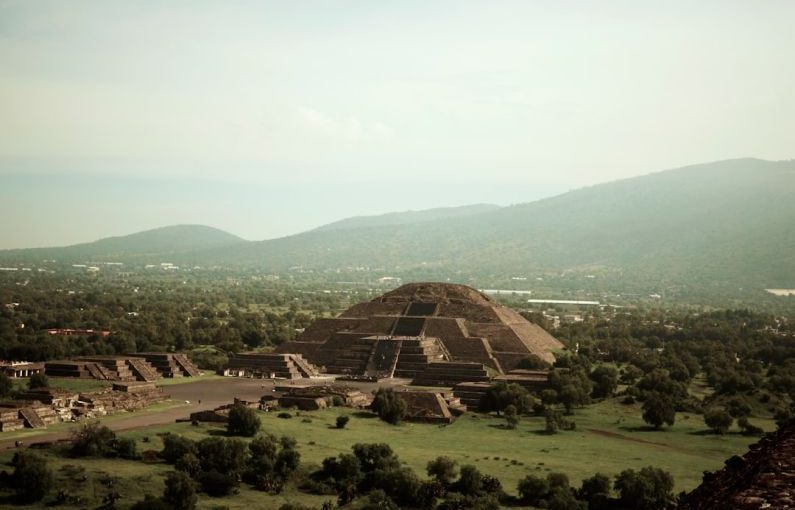 Teotihuacan - brown house on green grass field near green mountains during daytime