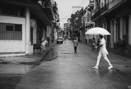 Havana Streets - man holding umbrella walking on gray road